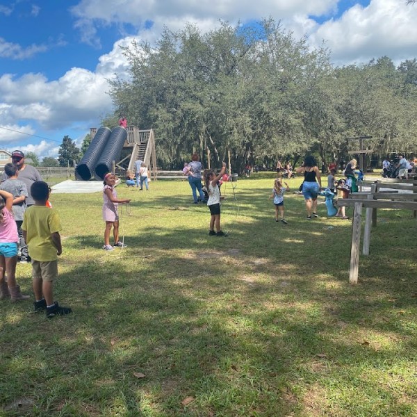 a group of people in a field flying a kite at the park